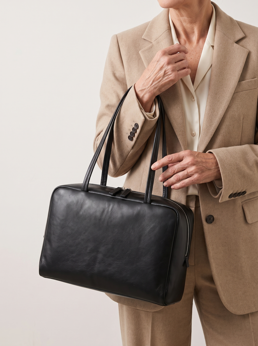 Klassische Handtasche aus Leder – Schwarz, in der Hand getragen